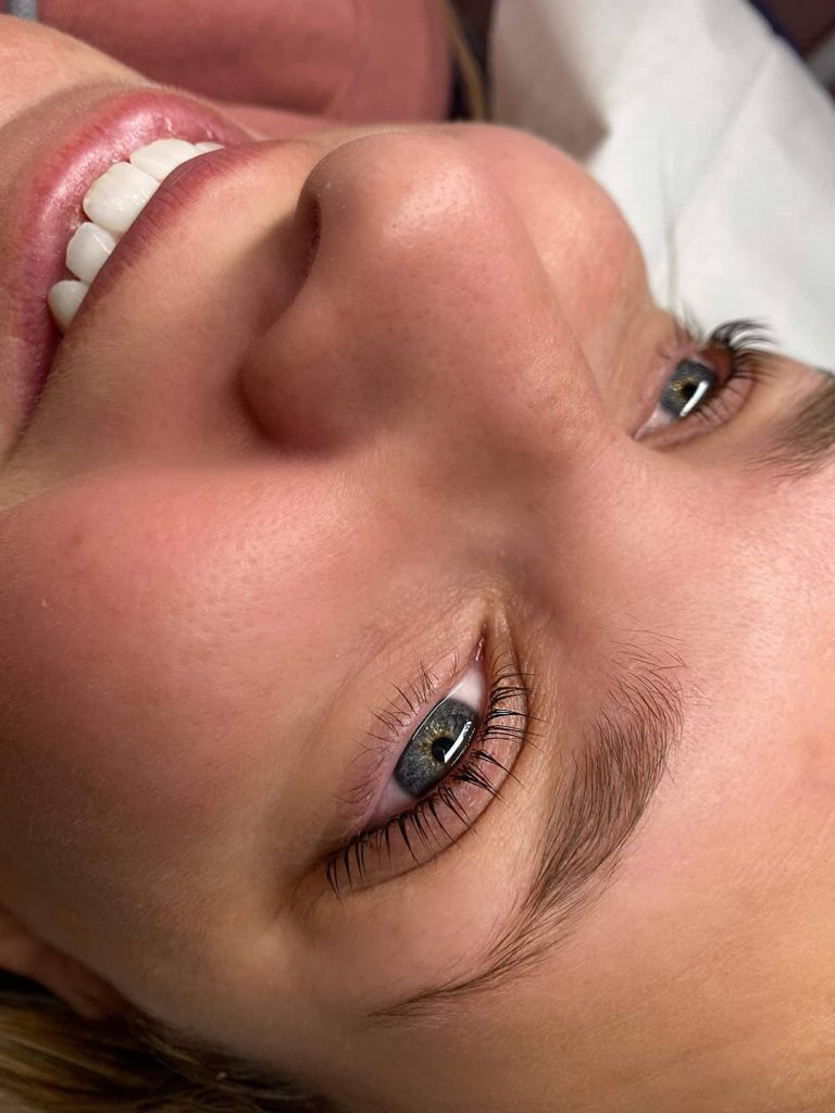 Jeune femme souriante aux yeux bleus dont le regard a gagné en profondeur suite à un rehaussement de cils