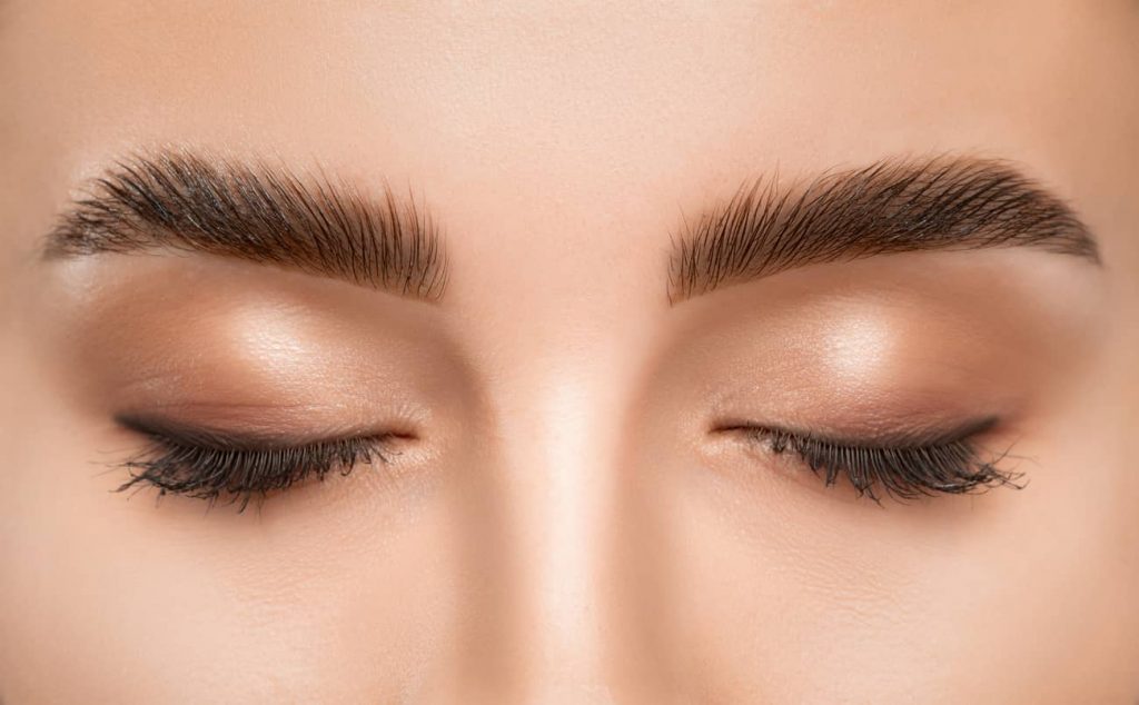 Gros plan sur les yeux et sourcils d’une femme qui a reçu le soin de lamination des sourcils (brow lamination)